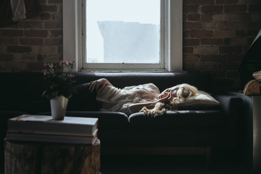Image d'une femme qui dors sur le canapé au lieu de dormir sur son lit.