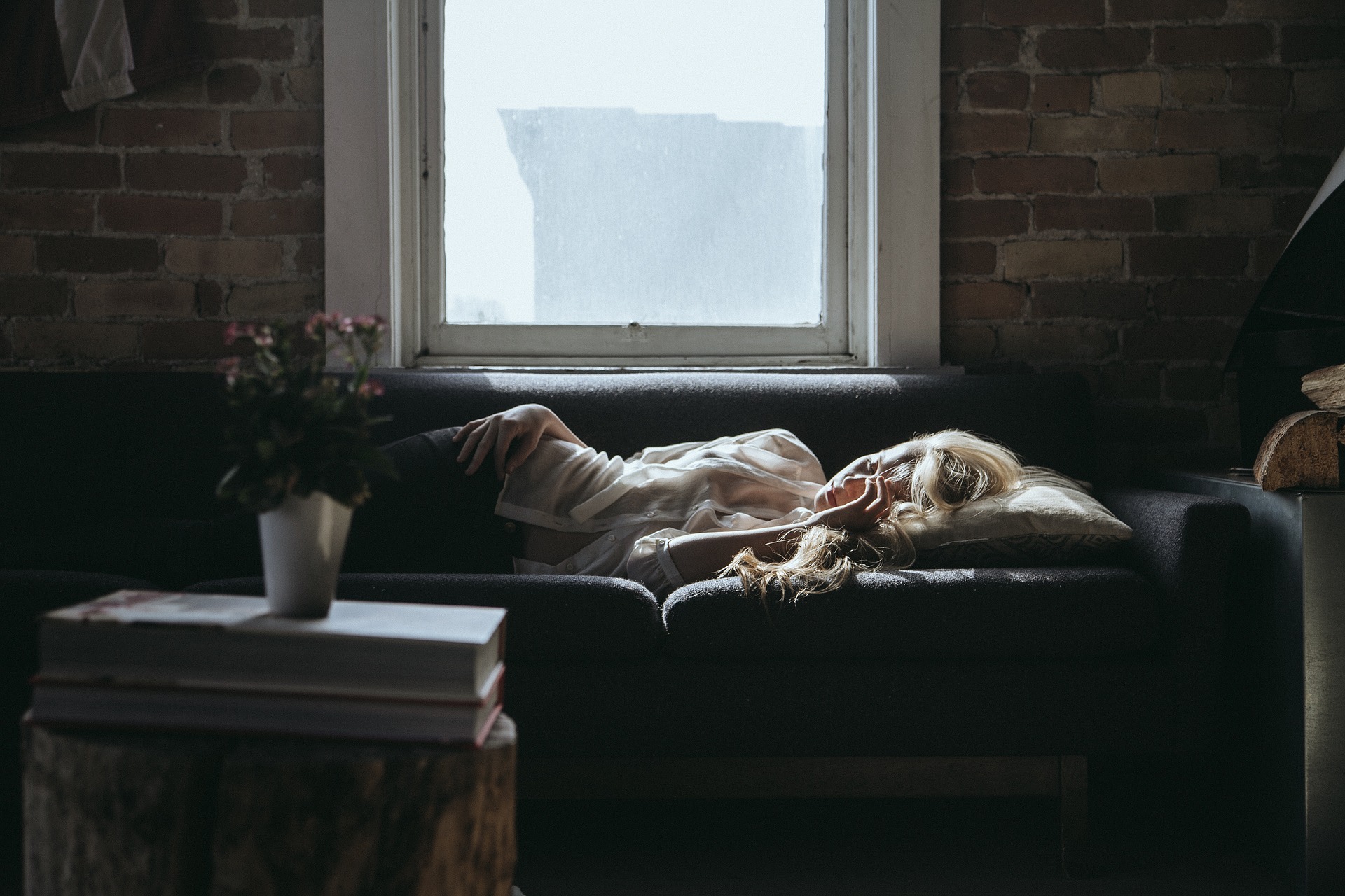 Image d'une femme qui dors sur le canapé au lieu de dormir sur son lit.
